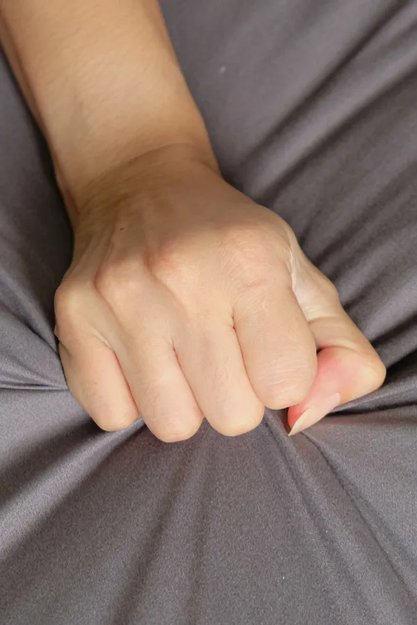 A close up of a woman's hand grabbing a gray bed sheet suggestively, representing successful O-Shot treatment for sexual wellness from Dr. Lashea Davis Roland in Silver Spring.