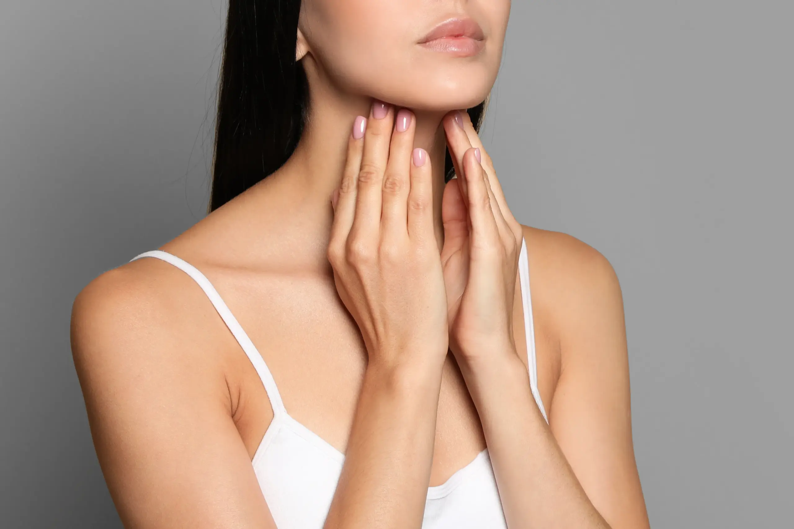 A woman in a white tank top touches her neck looking for signs of thyroid disorder. Get help for thyroid disorders from Dr. Lashea Davis Roland in Silver Spring.